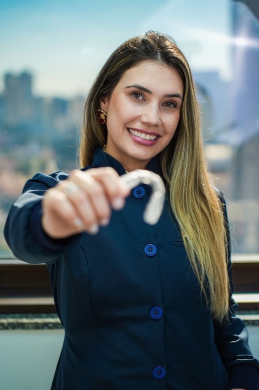Dra. Bárbara Barcaro, cirurgiã-dentista em Campinas, segurando um alinhador ortodôntico transparente